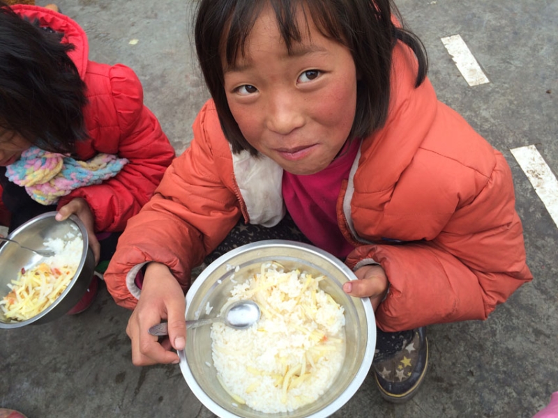 孩子们在吃饭,因为餐桌都被搬到教室当课桌去了,所以大冬天大家都蹲在